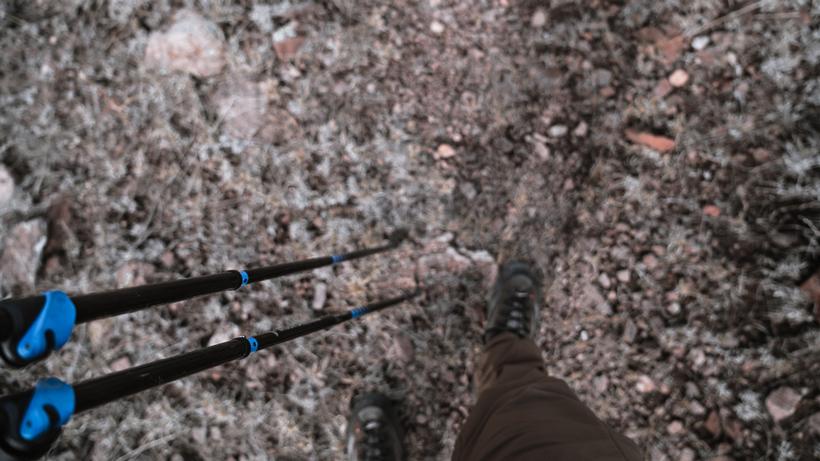 Close-up of trekking poles and a rocky path