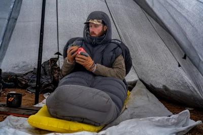 Brady Miller in Peax Solace sleeping bag in tipi shelter