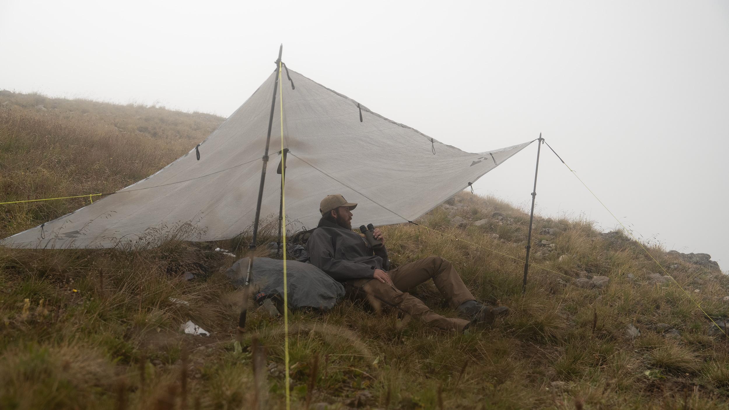 Brady Miller under the GOHUNT Dyneema Tarp weathering the storm